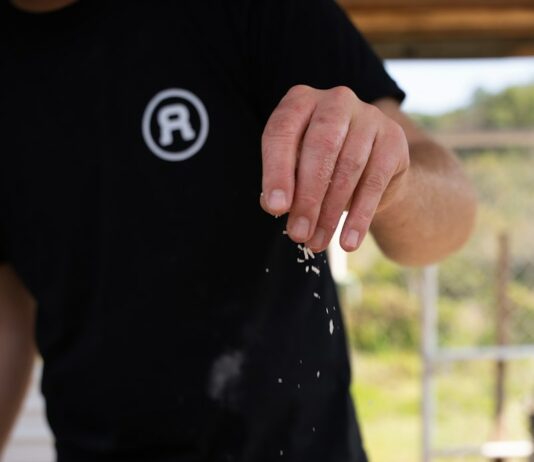 무더위의 끝자락, 더위를 잊게 하는 실내 활동으로 여름을 마무리하는 방법 a man sprinkling cheese on top of a pizza