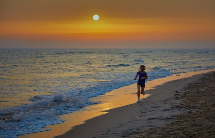 Photo by Vidar Nordli-Mathisen woman in black dress walking on beach during sunset