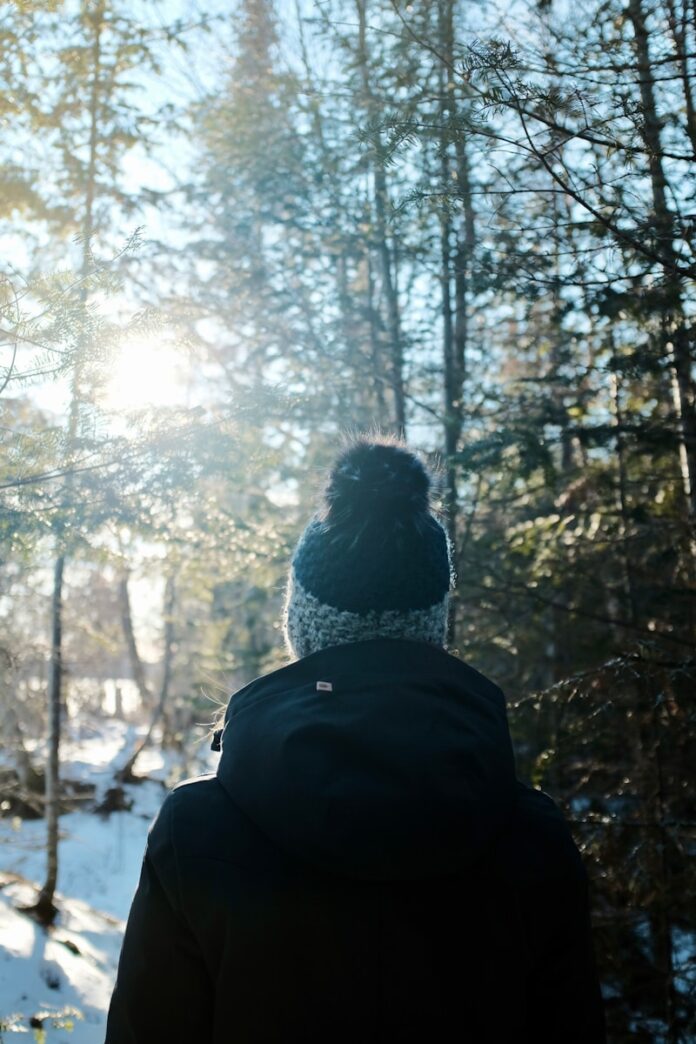 Photo by Jeff Ashton person in black jacket standing in front of trees during daytime