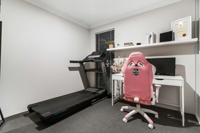 Photo by Alex Tyson A room with a treadmill and a desk