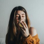“마음챙김 식사로 건강도 챙기고 다이어트 효과까지” a woman drinking a glass of water on a couch