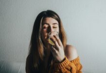 “마음챙김 식사로 건강도 챙기고 다이어트 효과까지” a woman drinking a glass of water on a couch