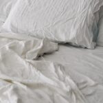 건강한 수면 루틴, 일상의 작은 변화가 삶을 바꾼다 A rumpled white duvet and pillows on a bed.