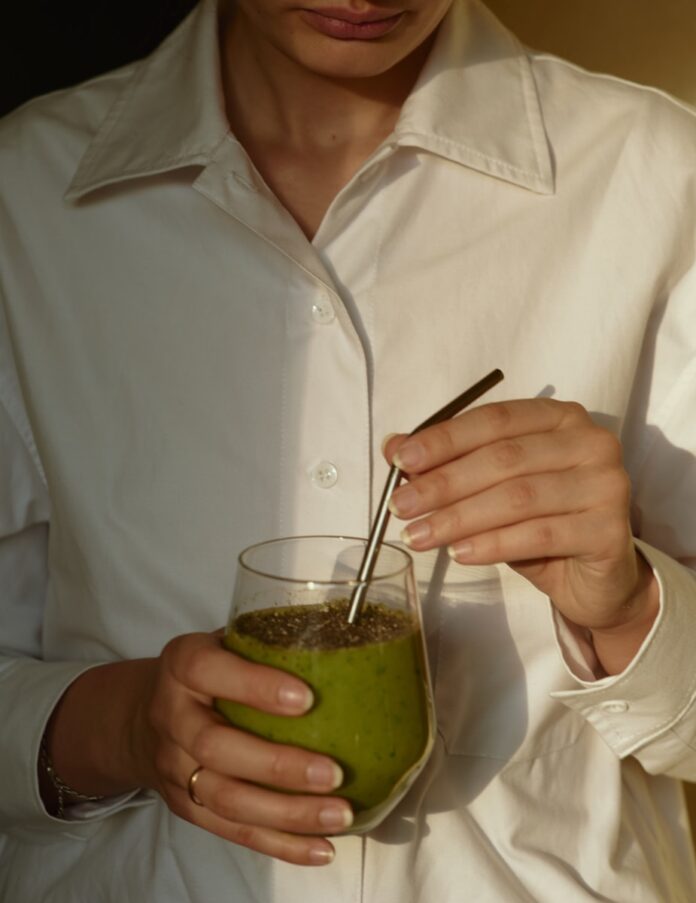 Photo by Victoria Aleksandrova person in white button up shirt holding clear drinking glass with green liquid